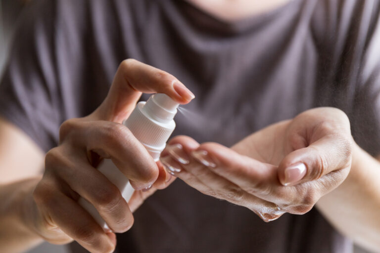 Close up view of woman person using small portable antibacterial hand sanitizer on hands. Coronavirus epidemic prevention concept